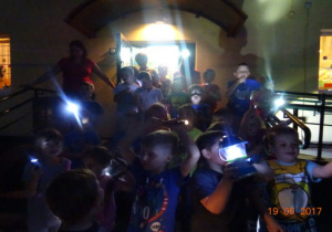 Dzieci z latarkami wychodzą z przedszkola.